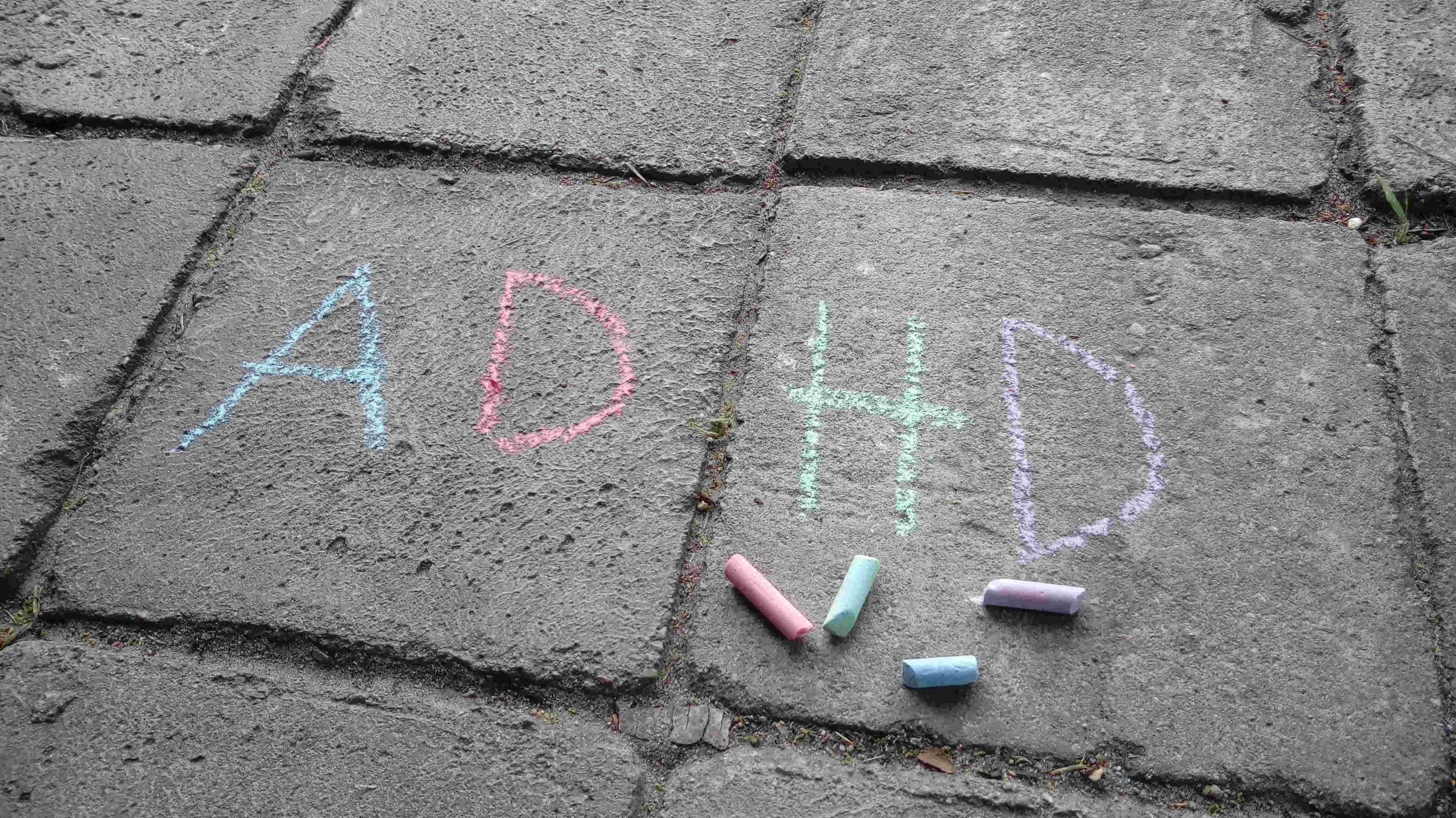 Napis ADHD zrobiony kredą na chodniku